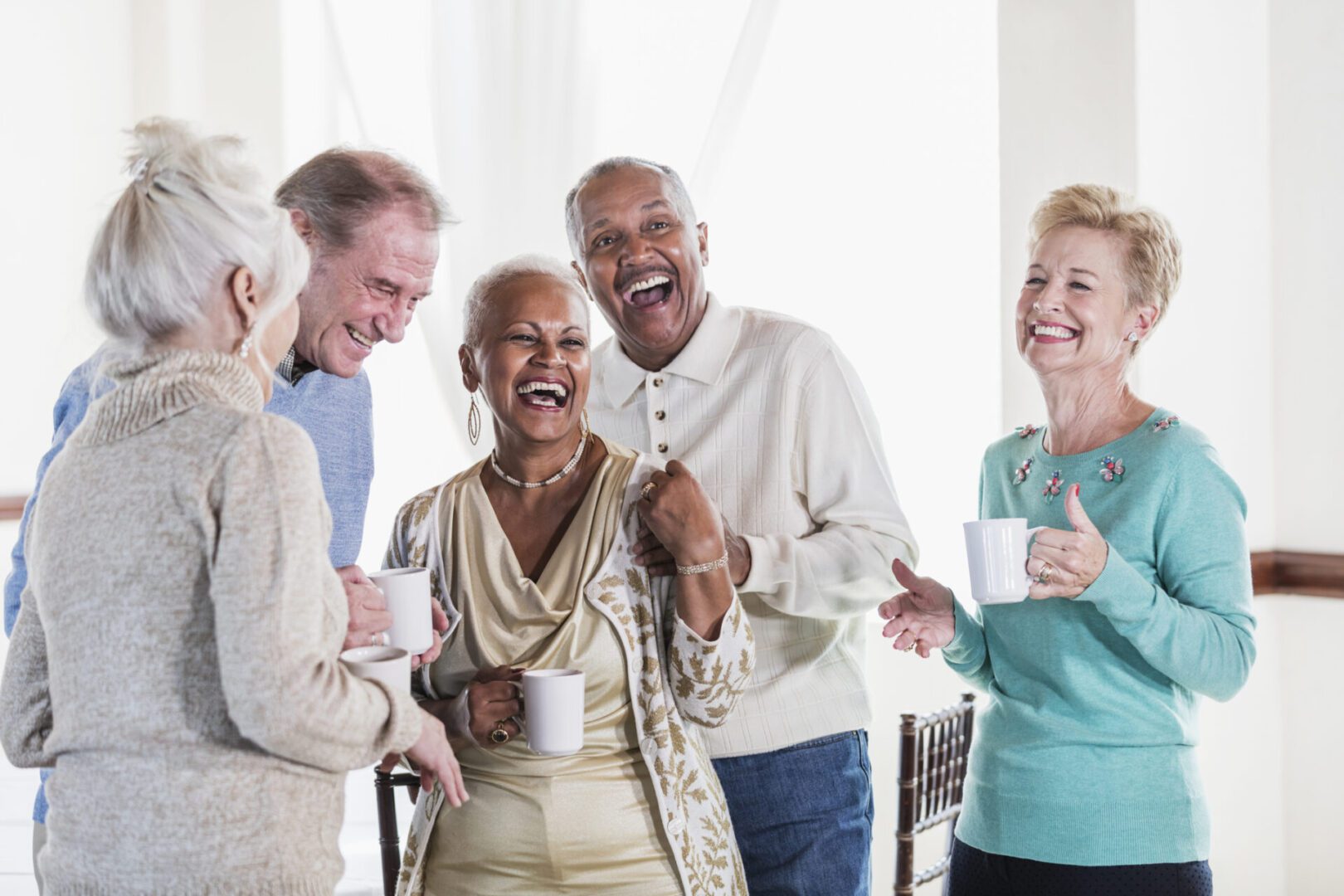 A joyful group of seniors enjoying coffee and laughter together.